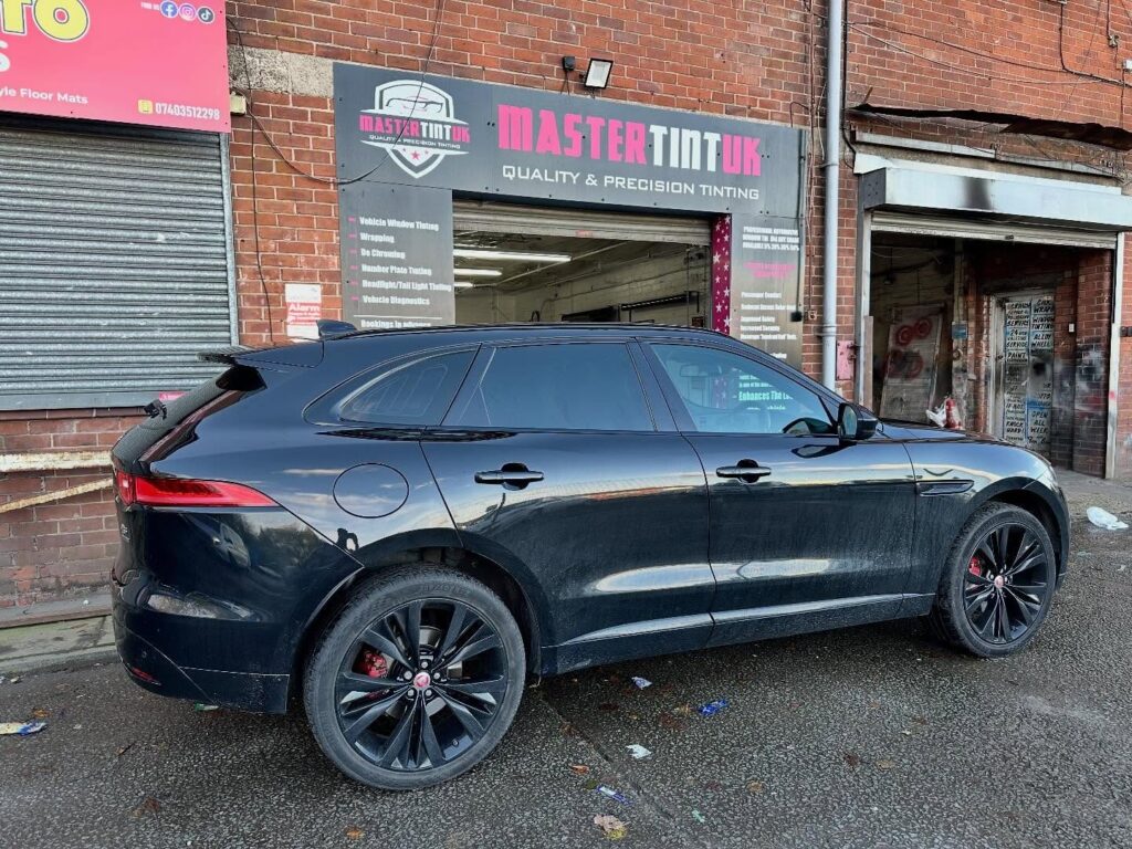 Black Jaguar F-Pace with tinted windows parked outside the Mastertint UK window tinting workshop in Bolton